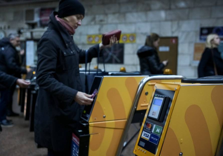 A passenger swipes a card against a terminal to ride the subway system in Kiev