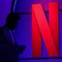 FILE PHOTO: A man stands next to a logo of Netflix during an event in Mumbai