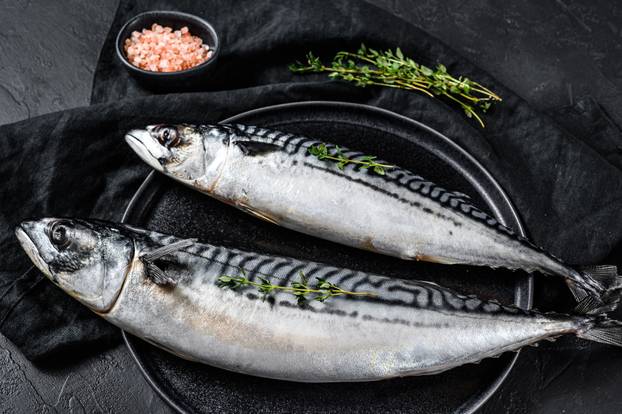Mackerel fish with thyme and pink salt. Fresh seafood. Black background. Top view