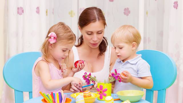 Mother with kids paint Easter eggs