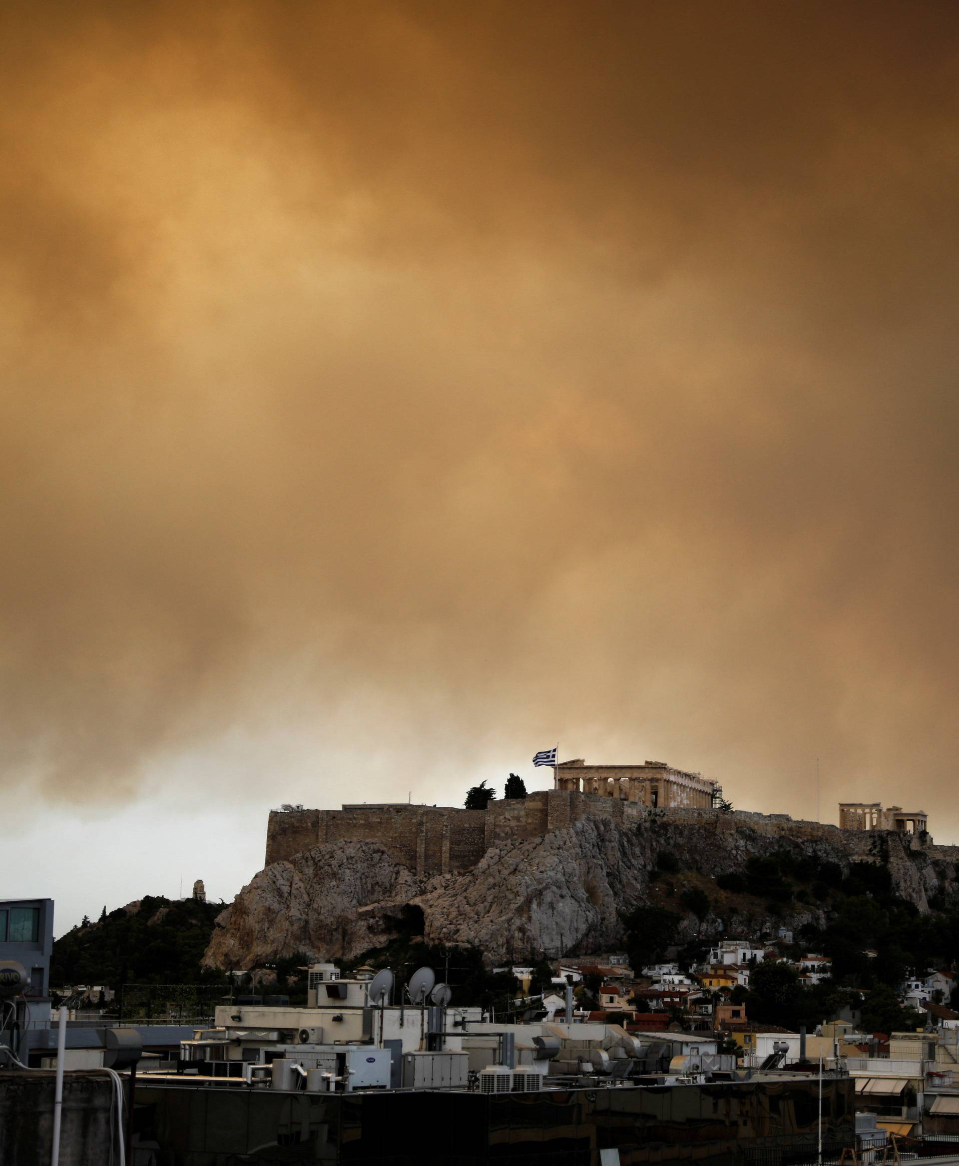 Smoke from a wildfire burning outside Athens is seen over the Parthenon temple atop the Acropolis hill in Athens