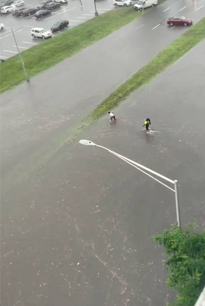 People wade through a flooded street in Yonkers