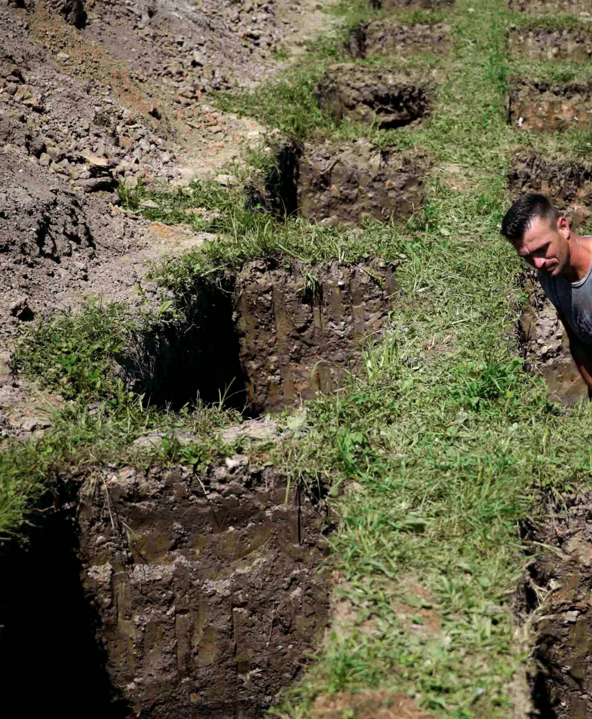 A worker digs graves at a memorial centre for Srebrenica Massacre victims in Potocari