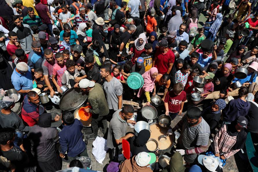 Palestinians gather to receive food from a charity kitchen, amid a hunger crisis, in Nuseirat