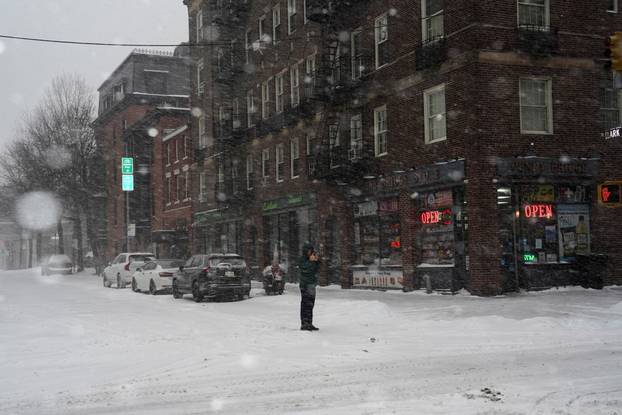 A pedestrian uses his mobile phone to photograph snowfall, in Brooklyn