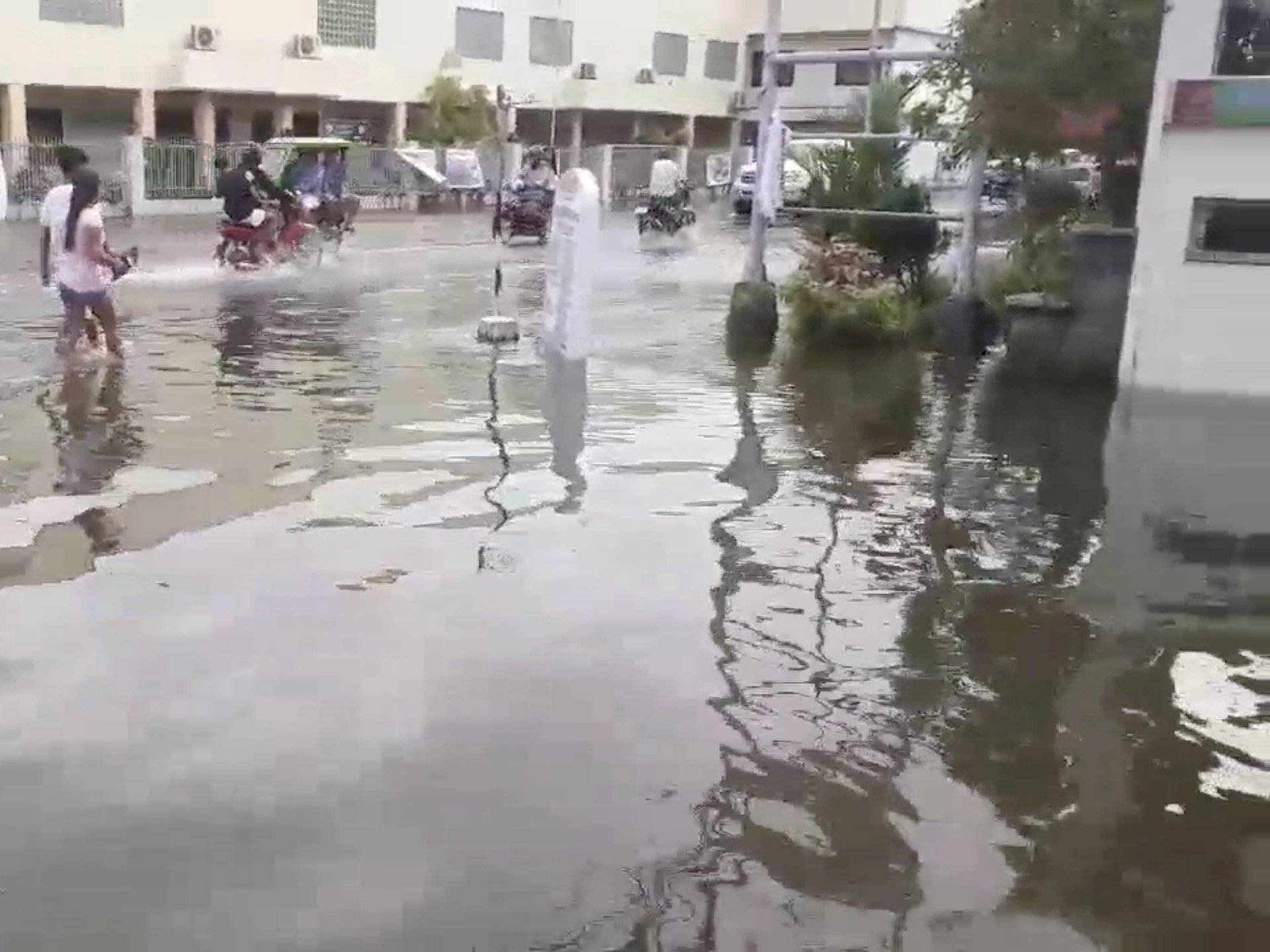 Pedestrians and vehicles move along a flooded street after a tropical depression descended upon Daet, Camarines Norte