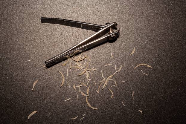 Cut fingernails and metal nail clipper on dark surface hygiene concept