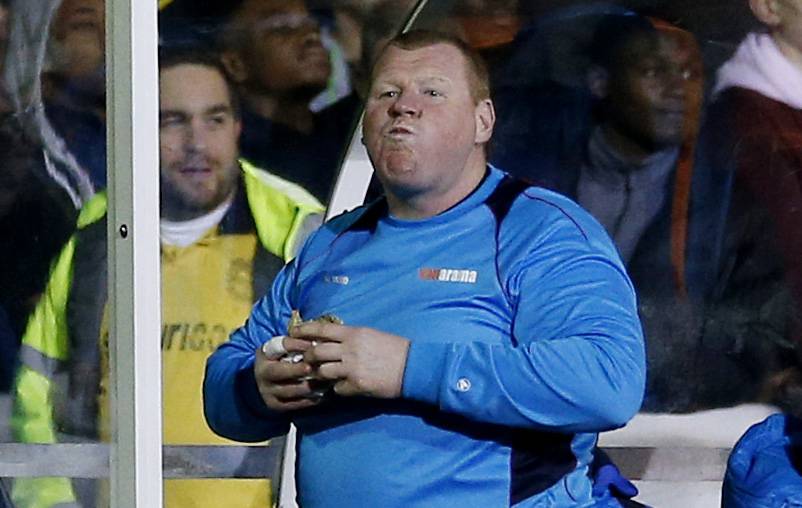 Sutton United's substitute Wayne Shaw eats a pie during the match