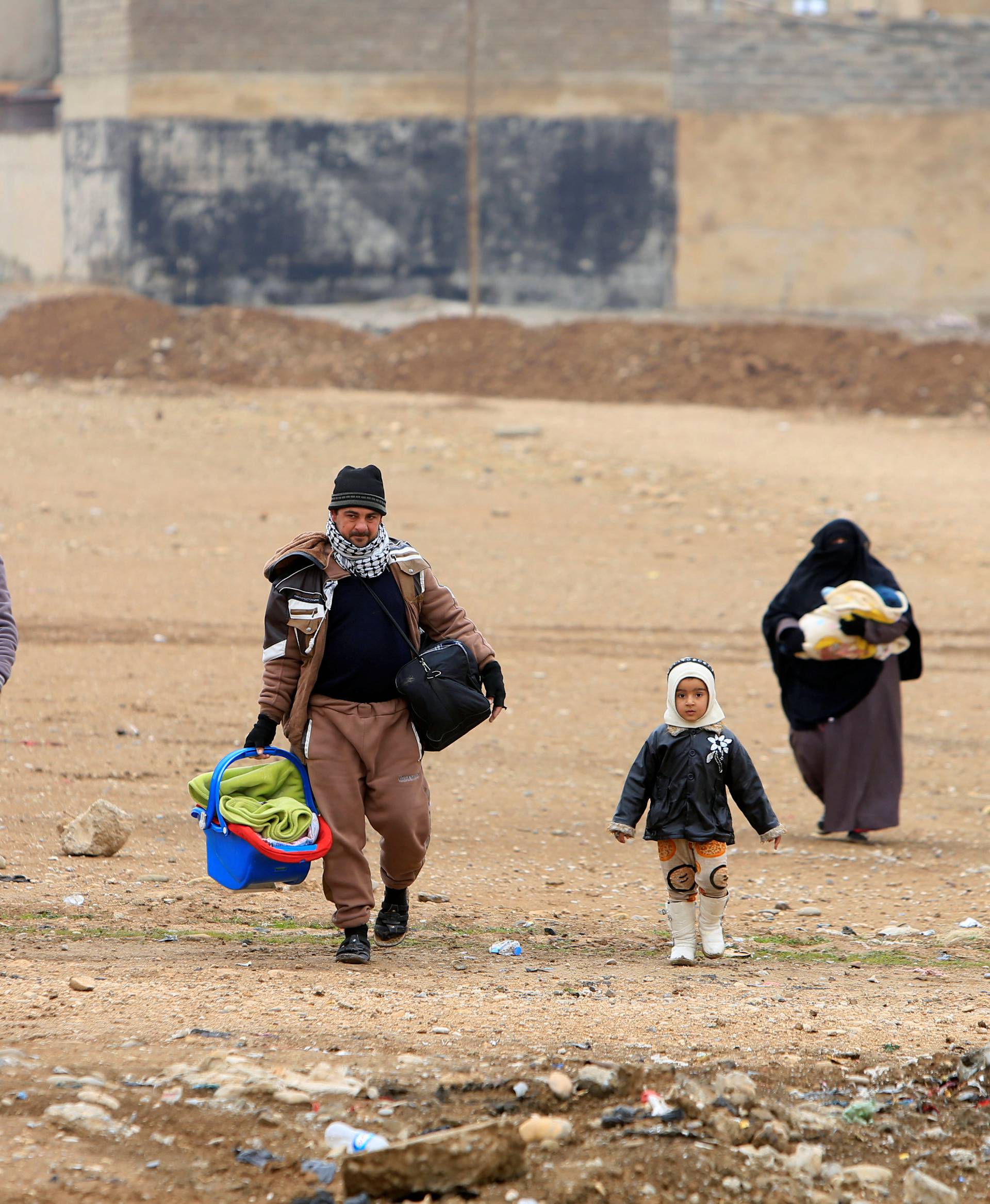 Displaced people, who are fleeing from Islamic State militants, carry their belongings as they walk in Mosul