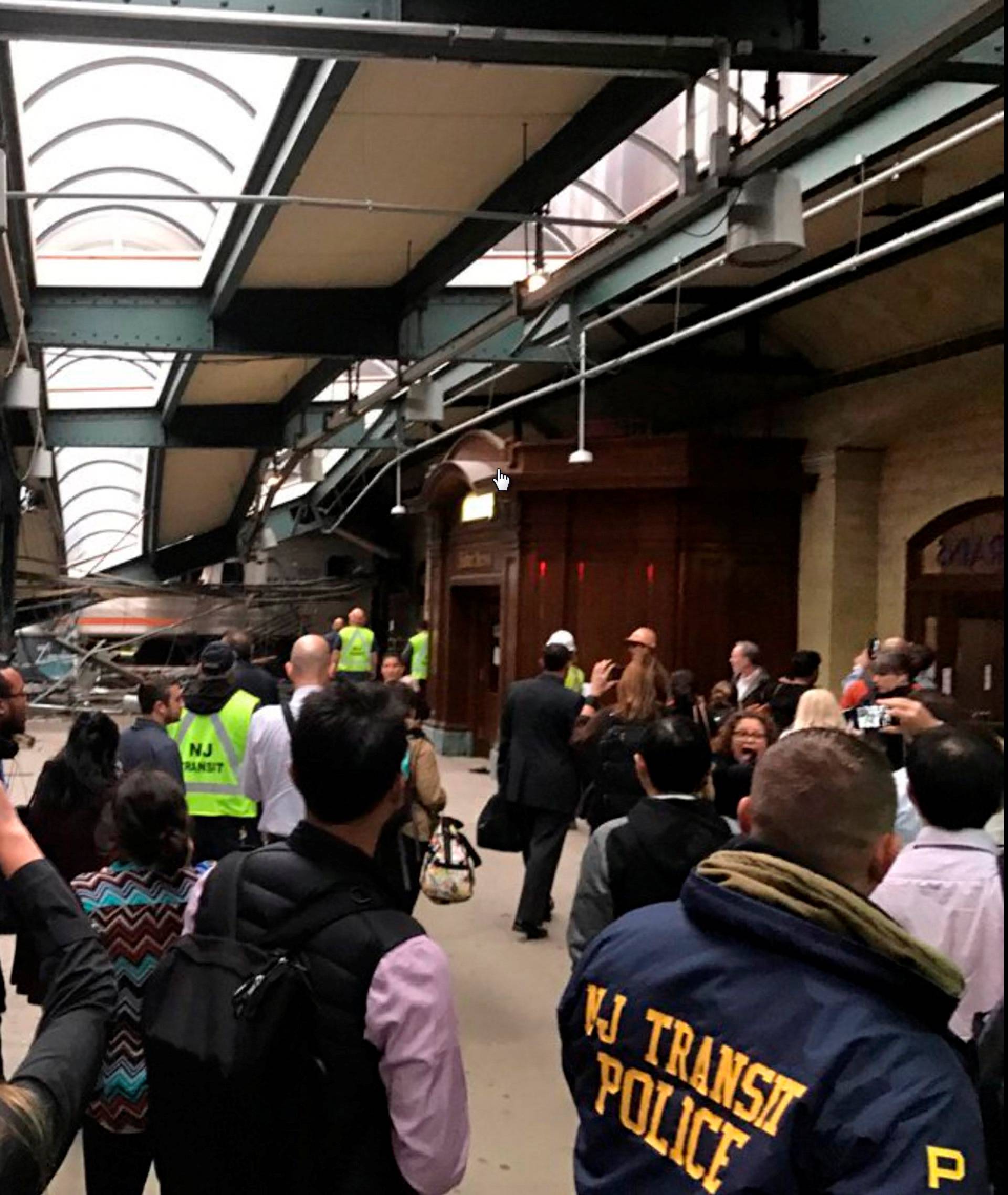 Onlookers view a New Jersey Transit train that derailed and crashed through the station in Hoboken