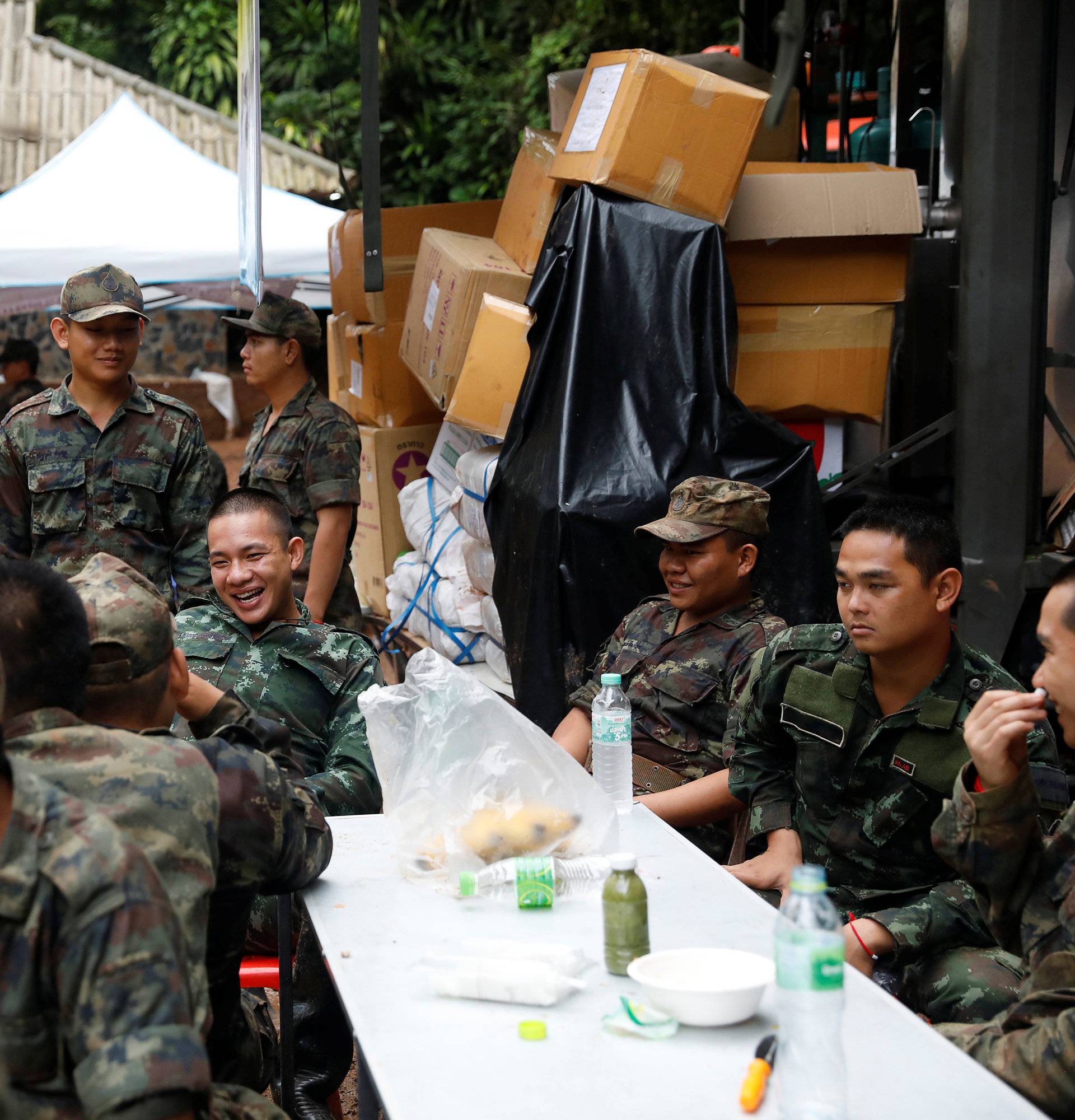 Soldiers pass their time near the Tham Luang cave complex, as members of an under-16 soccer team and their coach have been found alive according to local media, in the northern province of Chiang Rai