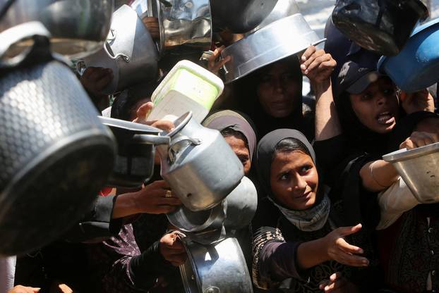 Palestinians wait to receive food from a charity kitchen, amid a hunger crisis, in Khan Younis