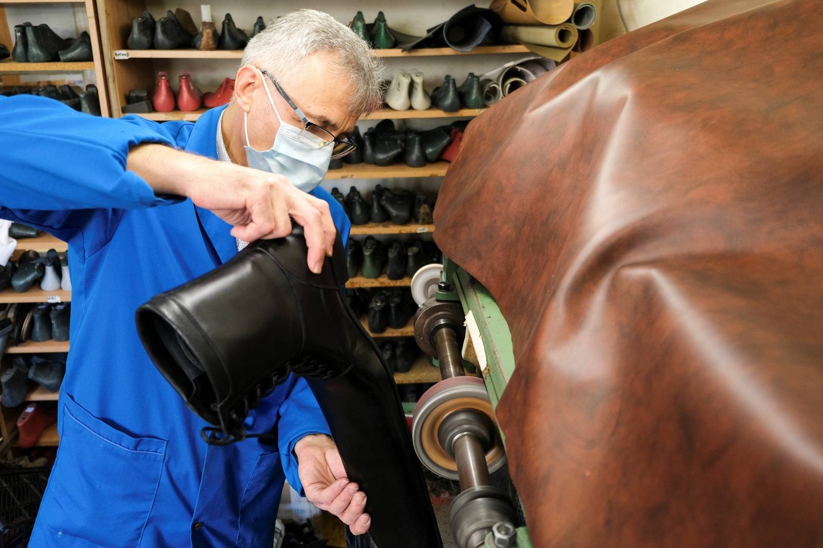 Romanian cobbler Grigore Lup polishes the soles of a pair of oversized winter boots while working on them