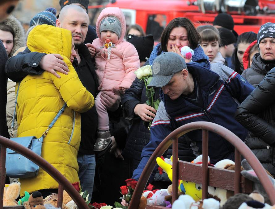 People mourn the victims of a shopping mall fire at a makeshift memorial in the Siberian city of Kemerovo