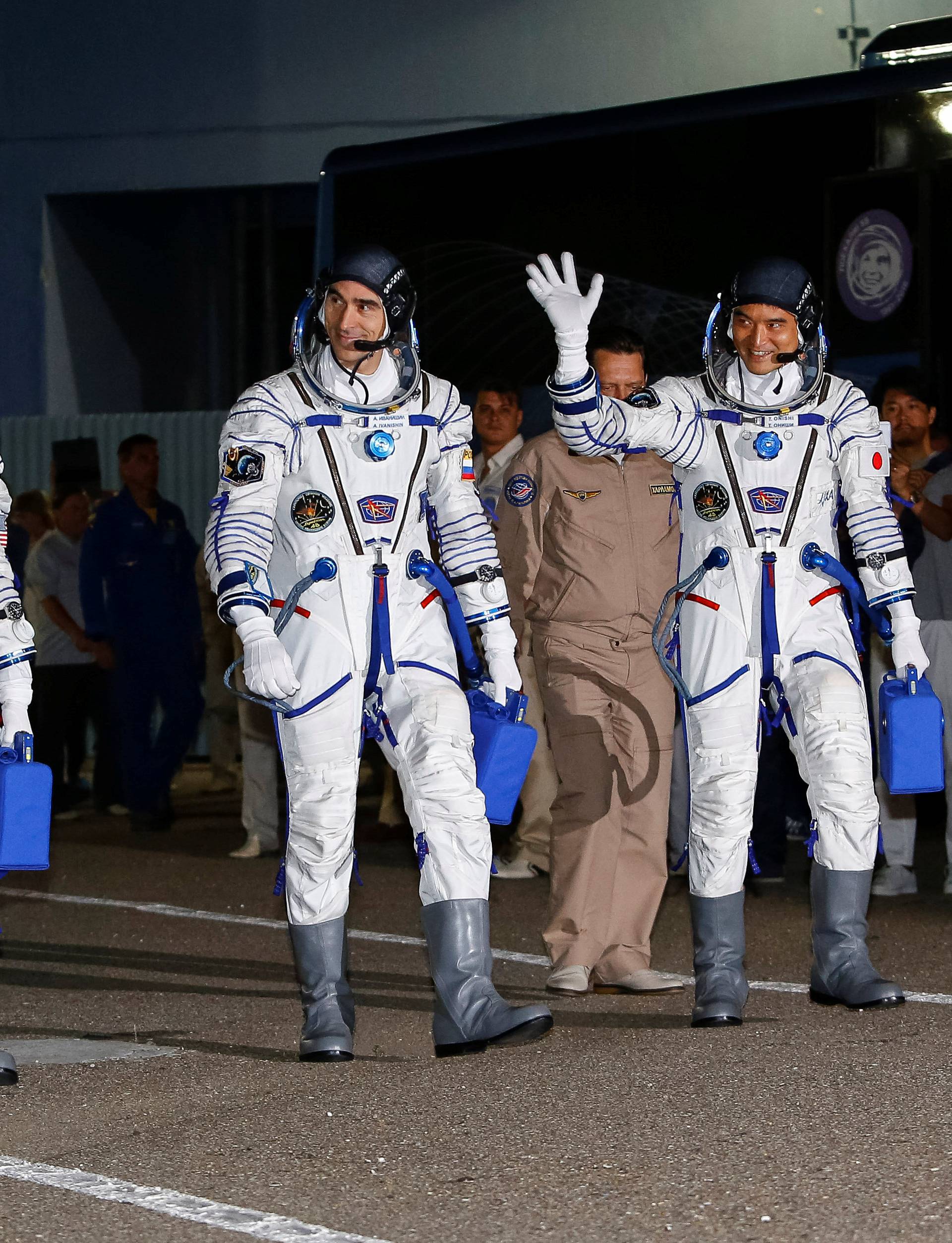 The ISS crew members Kate Rubins of the U.S., Anatoly Ivanishin of Russia and Takuya Onishi of Japan walk after donning space suits at the Baikonur cosmodrome, Kazakhstan