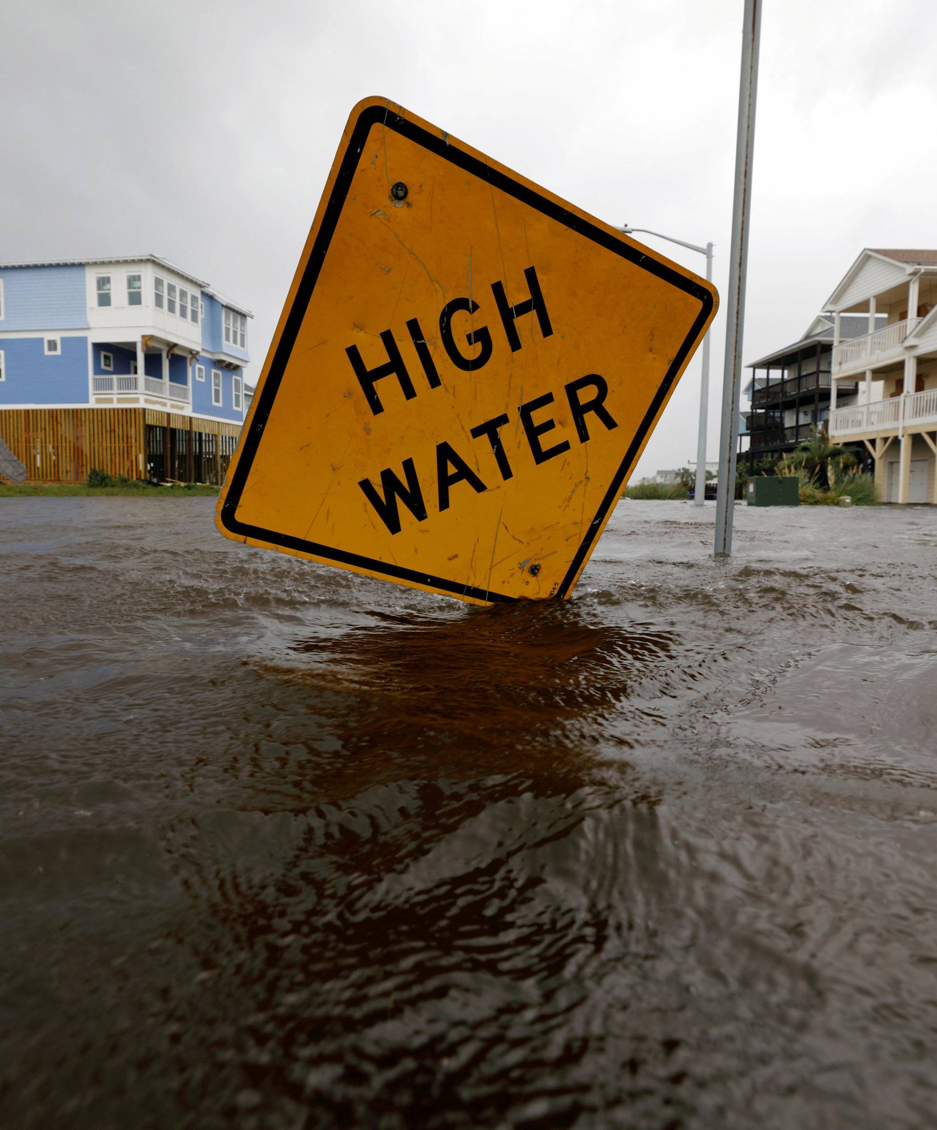 Flood waters lap at a high water warning sign that was partially pushed over by Hurricane Florence on Oak Island, North Carolina