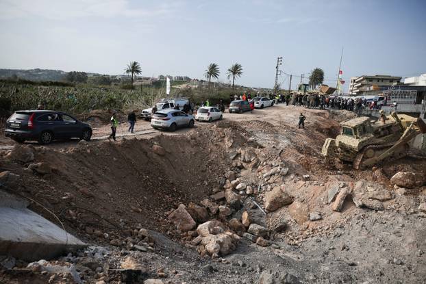 Displaced people cross the bridge linking southern Lebanon to the rest of the country, which was hit earlier in an Israeli strike, in Qasmiyeh