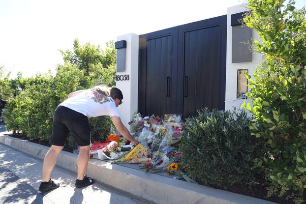 A person leaves flowers outside the home of late actor Matthew Perry in Pacific Palisades
