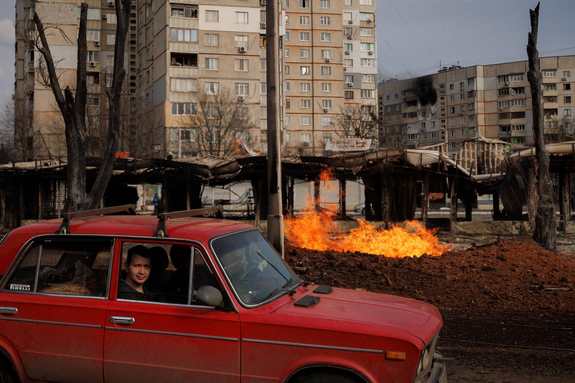 People drive past a fire at a gas pipeline after the neighbourhood was shelled from Russian positions in Kharkiv as Russia's attack on Ukraine continues