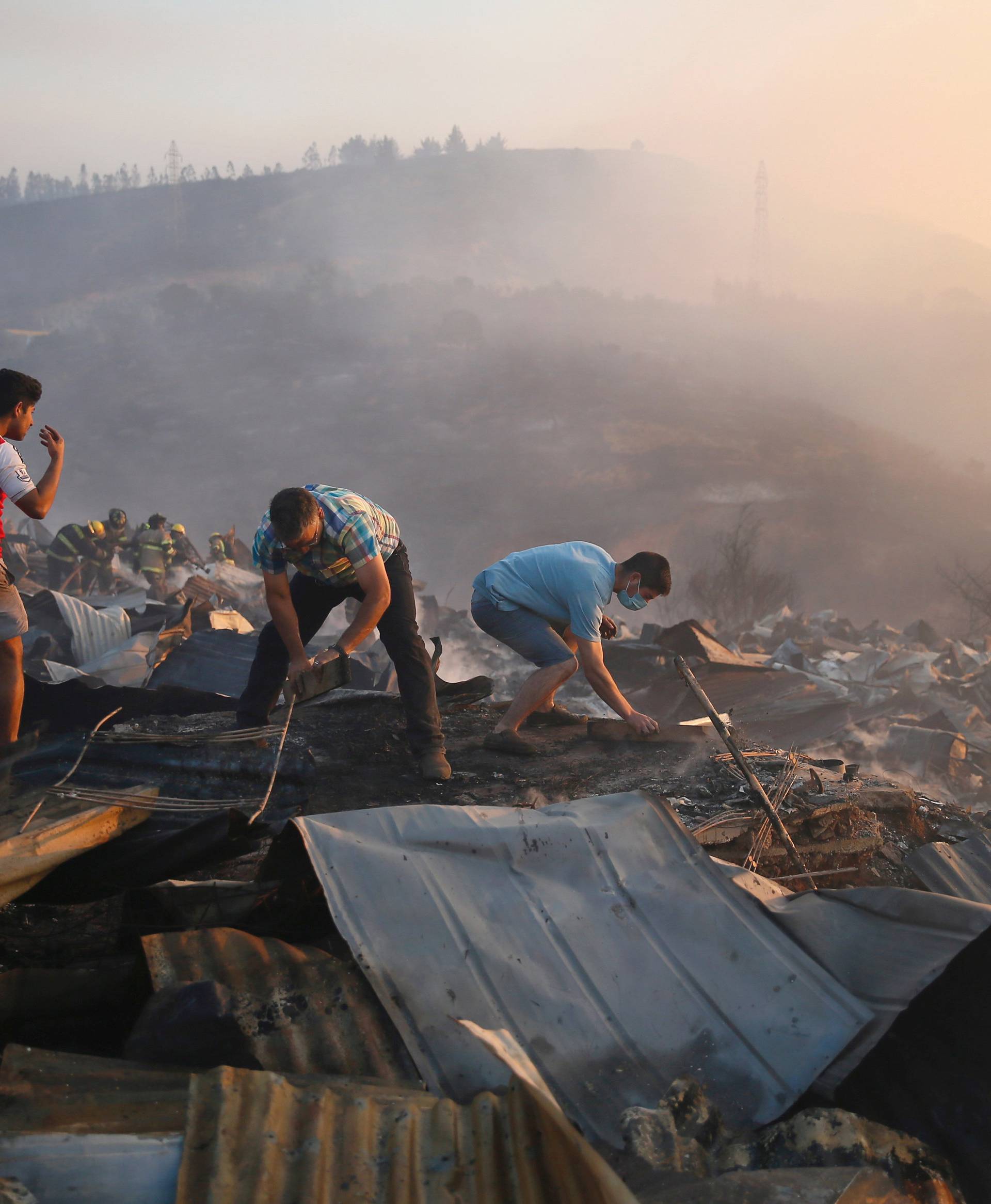 Residents survey the damages and remove the remnants of burned houses on a hill, where more than 100 homes were burned due to a forest fire but there have been no reports of death, local authorities said in Valparaiso, Chile.