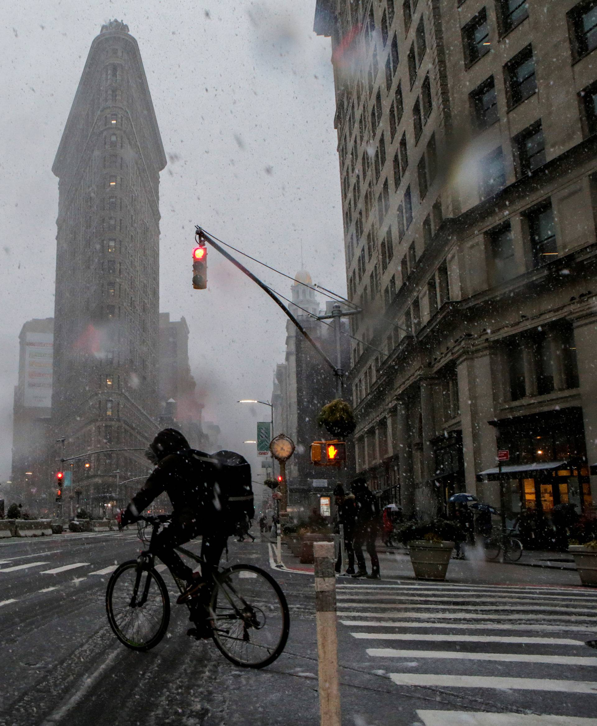 A man rides his bike near the Flatiron Building during a snowstorm in New York City, New York