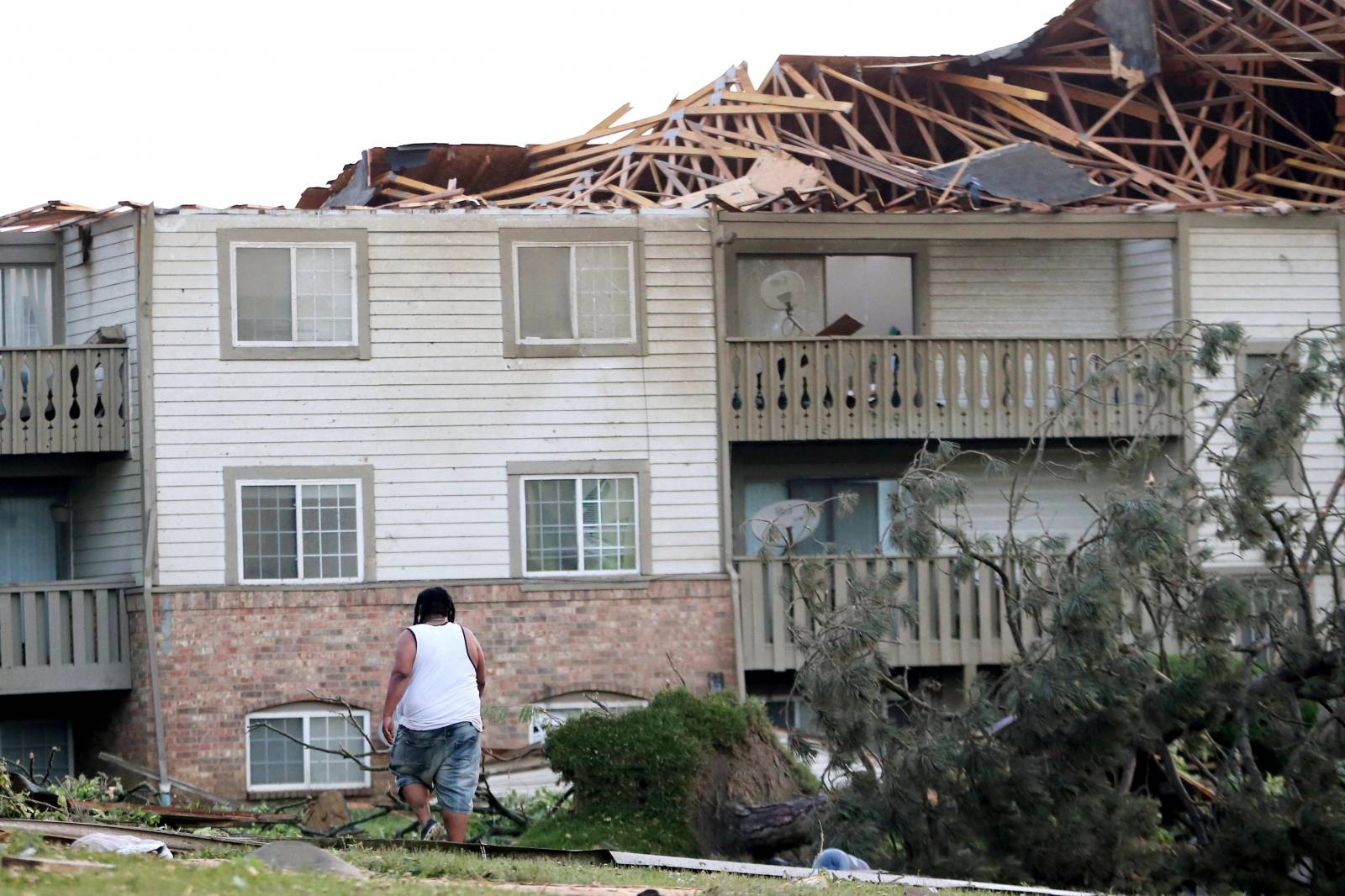 A man walks through the scattered debri outside his apartment building in the morning after a tornado touched down overnight in Trotwood