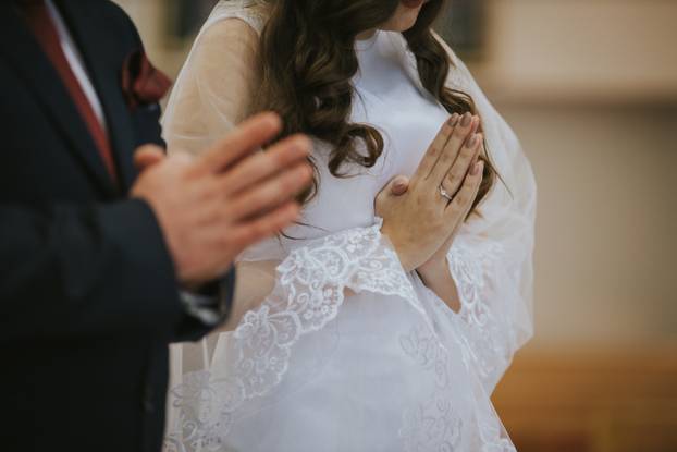 Selective focus shot of bride and groom hands praying