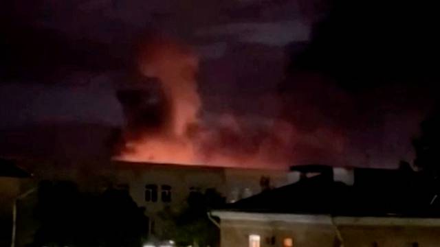 A plume of smoke is illuminated by a flash of light amid a drone attack in Pskov