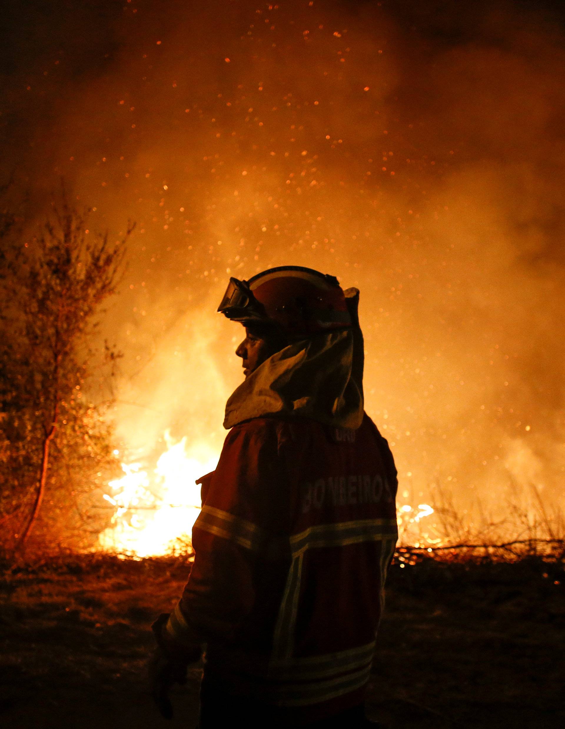 A firefighter is seen near flames from a forest fire in Cabanoes near Lousa