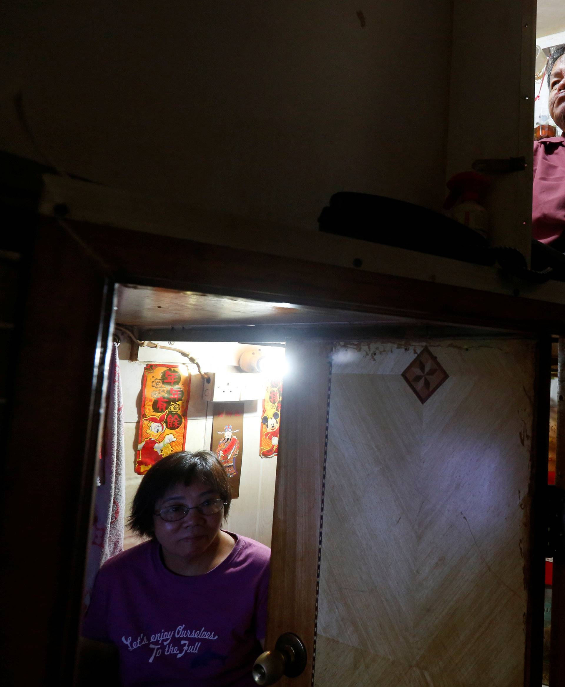 Unemployed Hong Kong residents Lam, 60, and Kitty Au, 63, rest inside their upper and lower decks partitioned units, or "coffin units", in Hong Kong