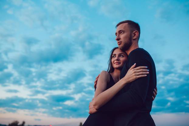Love story . Couple at sunset. On the background of the sky. Clouds.