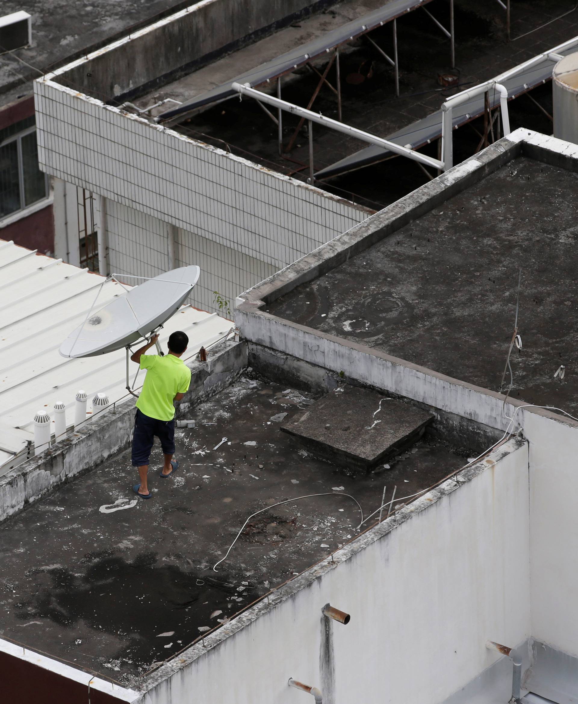 A man carries a satellite television receiver away form the top of a hotel as Typhoon Mangkhut approaches in Shenzhen