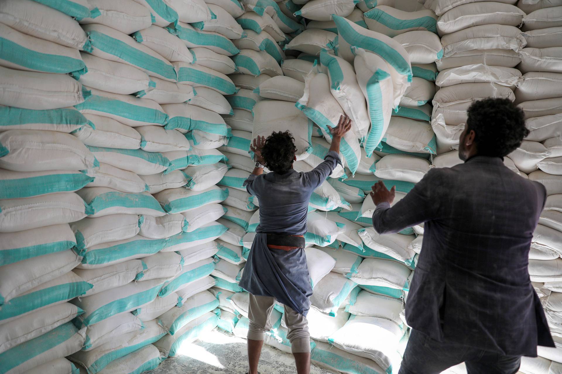 FILE PHOTO: Workers handle sacks of wheat flour at a World Food Programme food aid distribution center in Sanaa