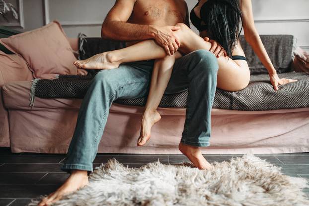 Male and female person hugs on couch, erotica