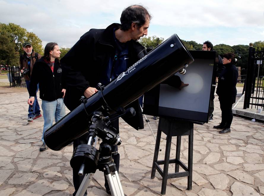A man points to where Mercury planet is on a reflection of the sun made with a telescope outside Buenos Aires' planetarium