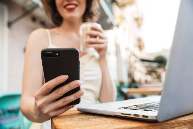 Cropped image of woman in straw hat using smartphone