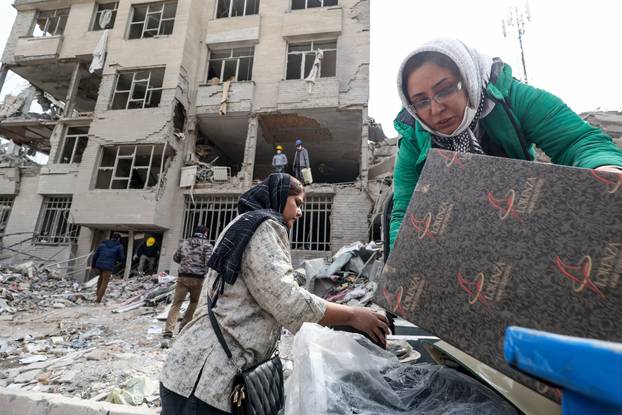 A family gathers the remaining furniture from an apartment damaged by an airstrike, in Tehran
