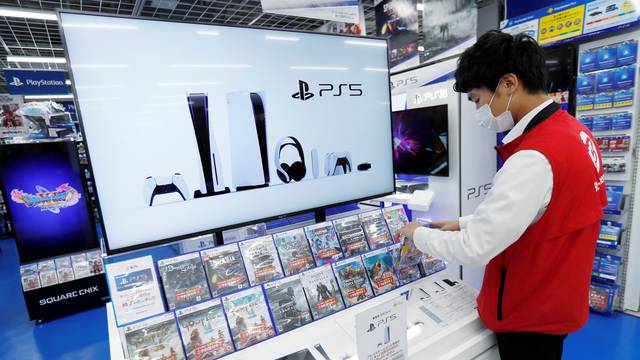 An employee of the consumer electronics retailer chain Bic Camera works at the promotion display of the Sony PlayStation 5 game console and its gaming software, ahead of the game console's official launch, in Tokyo