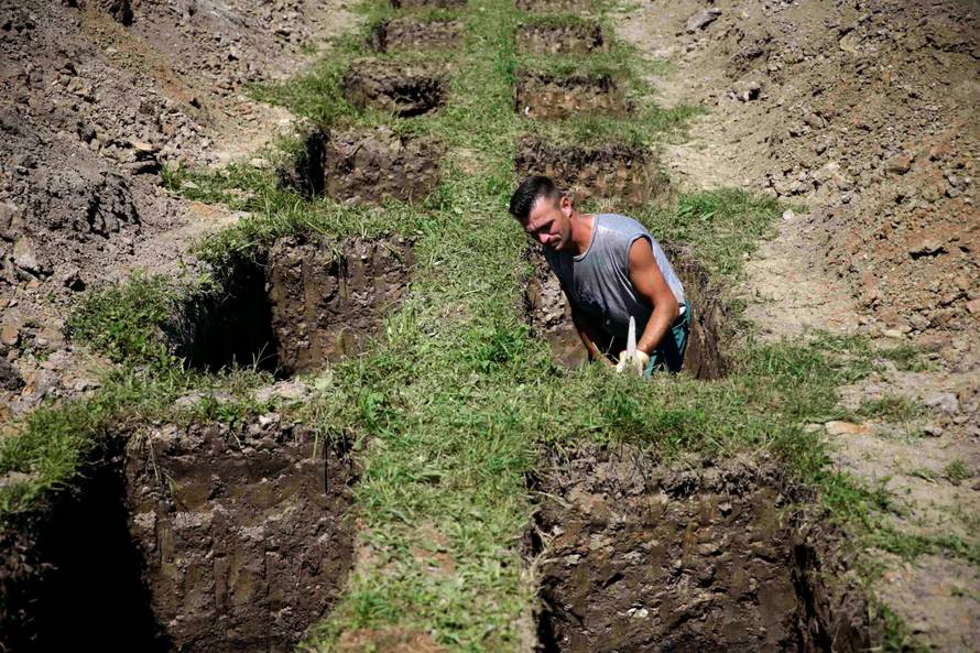 A worker digs graves at a memorial centre for Srebrenica Massacre victims in Potocari