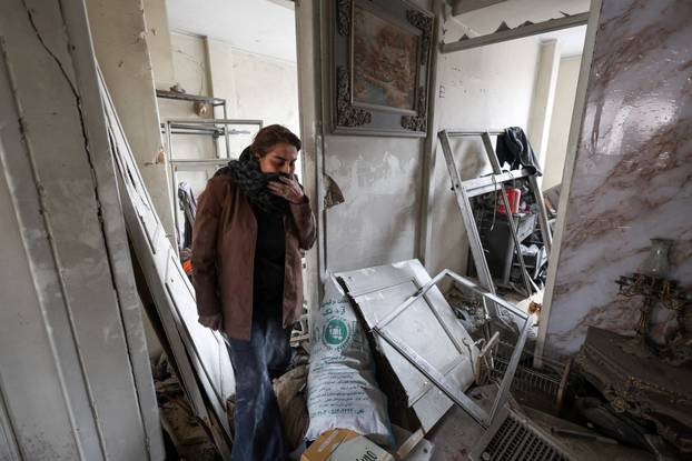 A woman inspects the damage inside her apartment after it was hit by an airstrike, in Tehran