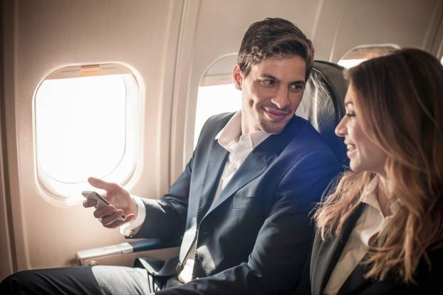Businesspeople On Aeroplane With Smartphone