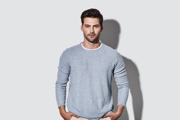 Perfect man. Handsome young man in casual wear looking at camera and smiling while standing against grey background