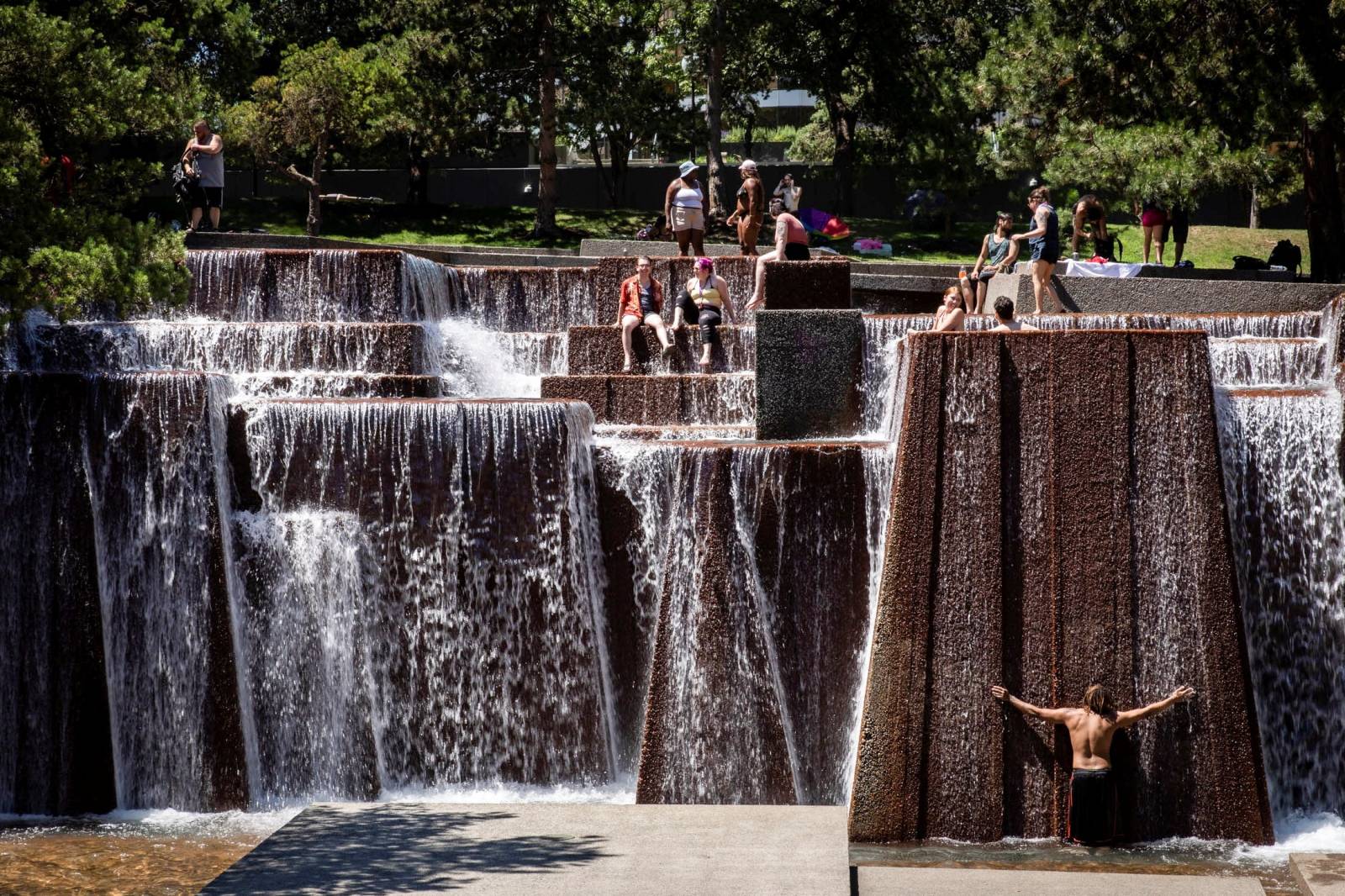 People cool off in a public fountain during hot weather in Portland