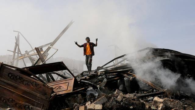 FILE PHOTO: A worker reacts as he stands on the wreckage of a vehicle oil and tires store hit by Saudi-led air strikes, in Sanaa
