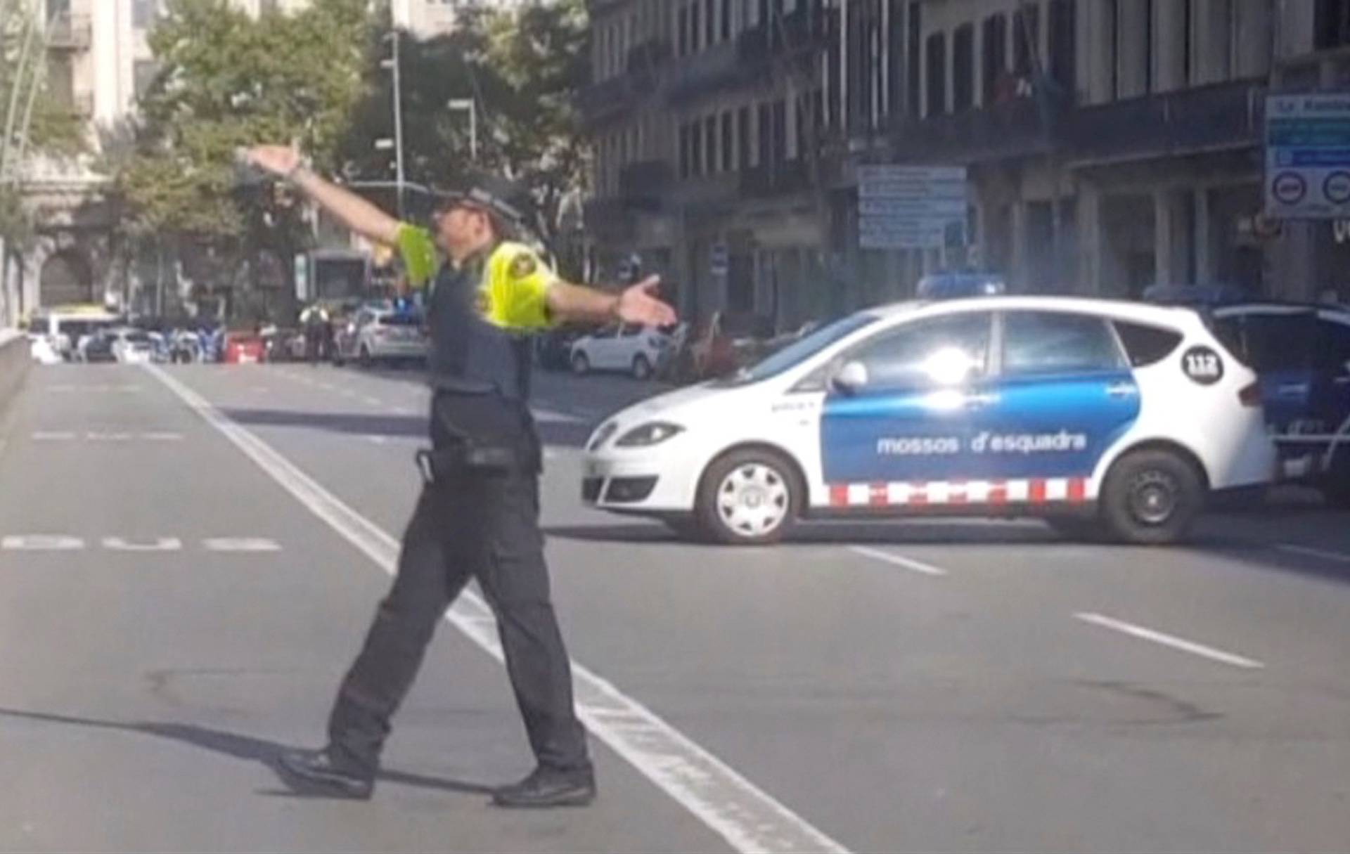 A still image from video shows a police officer gesturing while walking across a road, after a van crashed into people in the centre of Barcelona