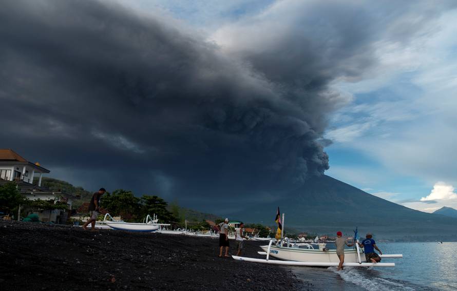 Indonesia's Mount Agung volcano erupts as fishermen pull a boat onto the beach in Amed, Bali