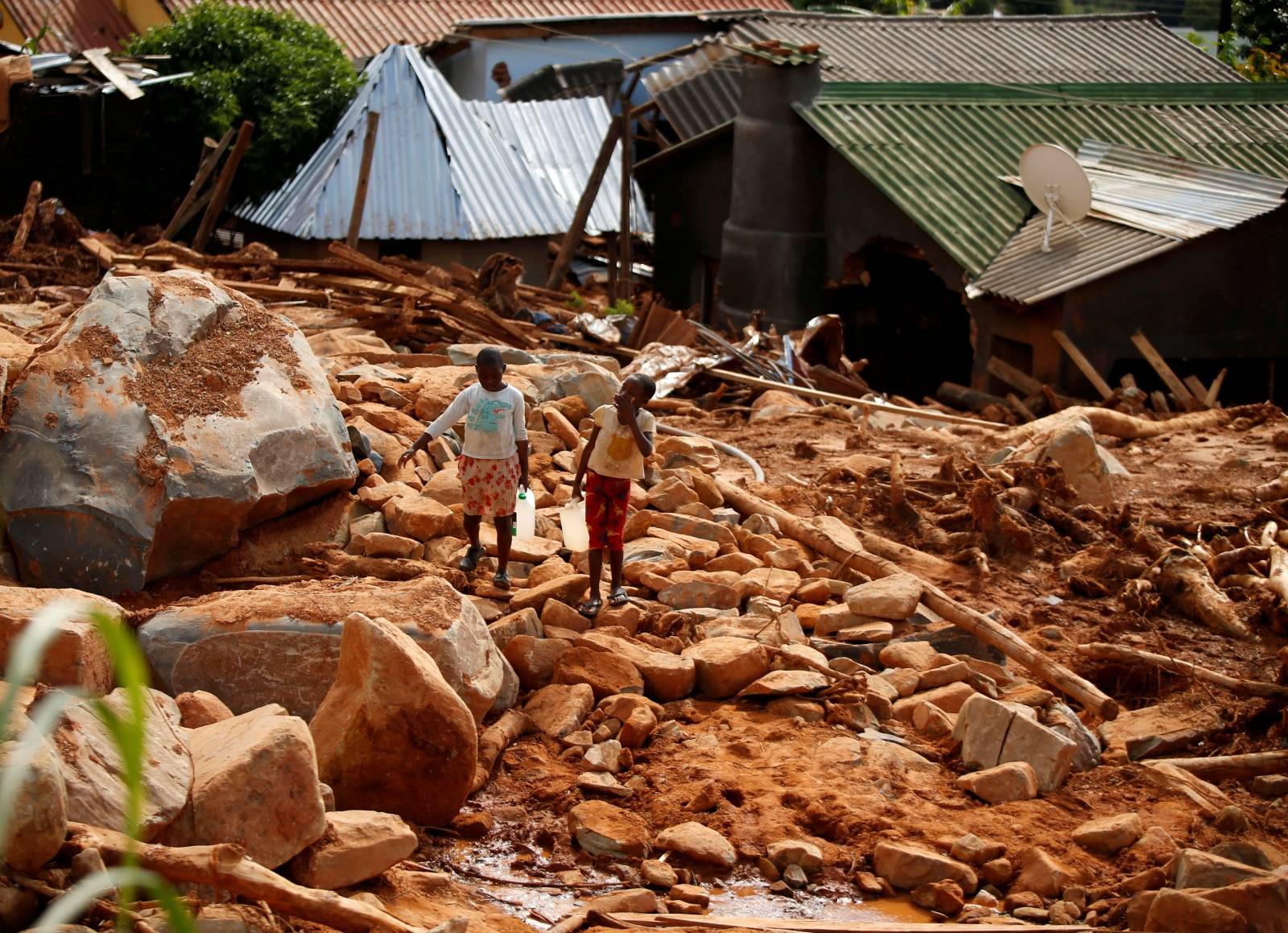 Children carry drinking water over debris created by Cyclone Idai at Peacock Growth Point in Chimanimani