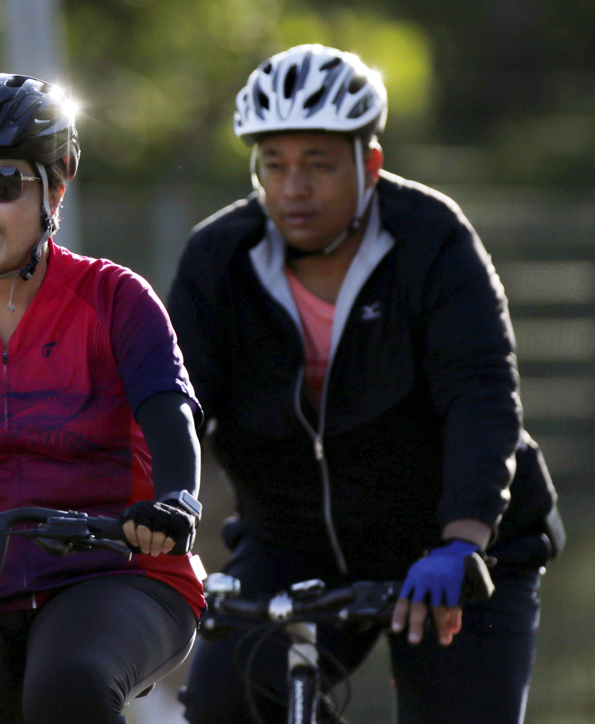 Brazil's President Dilma Rousseff rides her bicycle accompanied by bodyguard near the Alvorada Palace in Brasilia