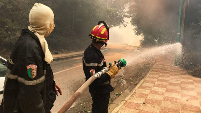 A firefighter uses a water hose during a forest fire in Ain al-Hammam village