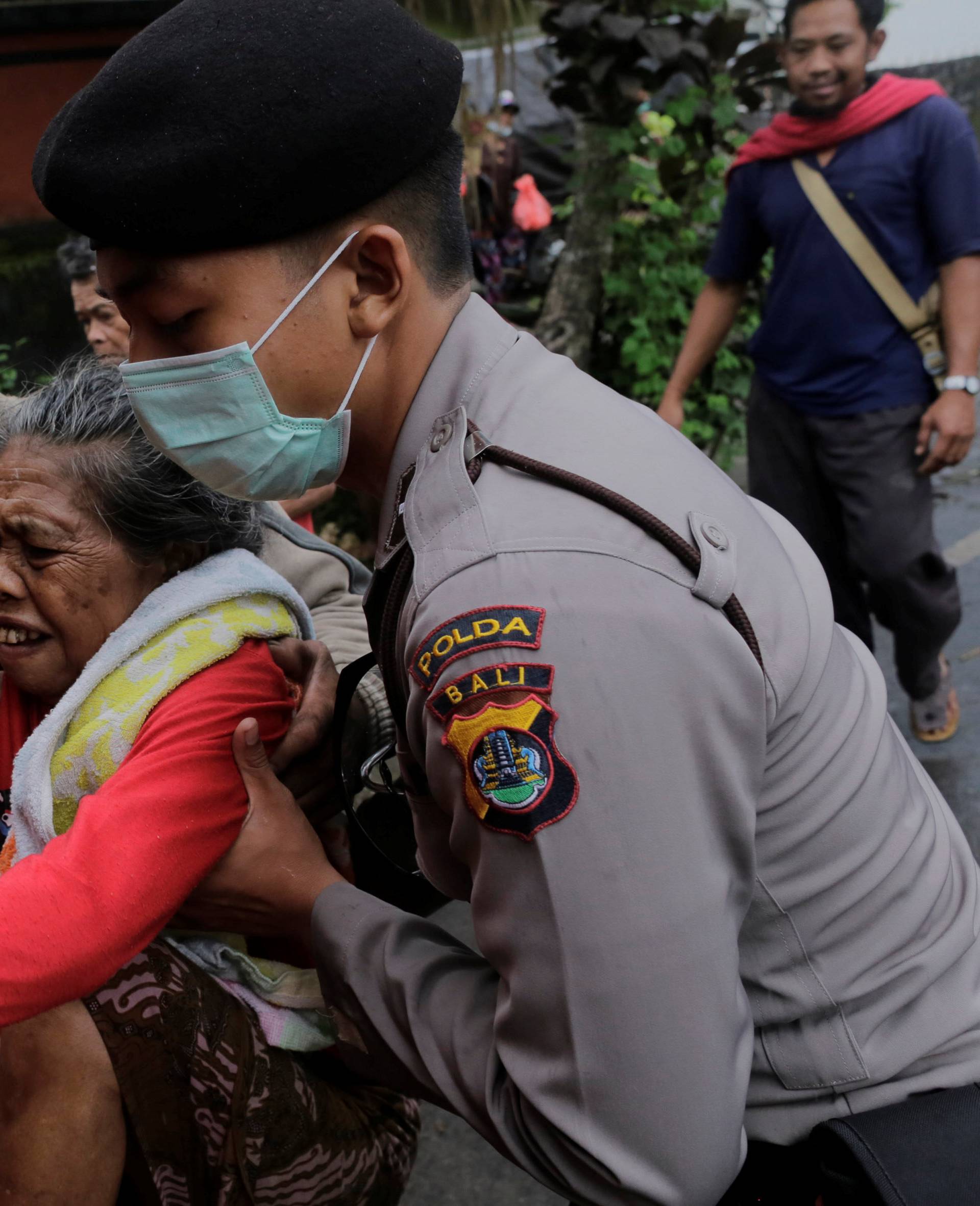 Police evacuate a villager from inside the exclusion zone due to the eruption of Mount Agung volcano in Karangasem